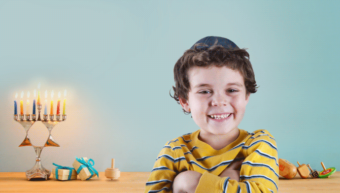 Kid standing in front of a menorah and a spinning dreidel against sky blue backdrop