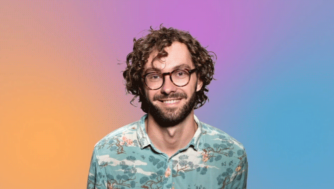 Man in front of pastel peach, pink, and blue background