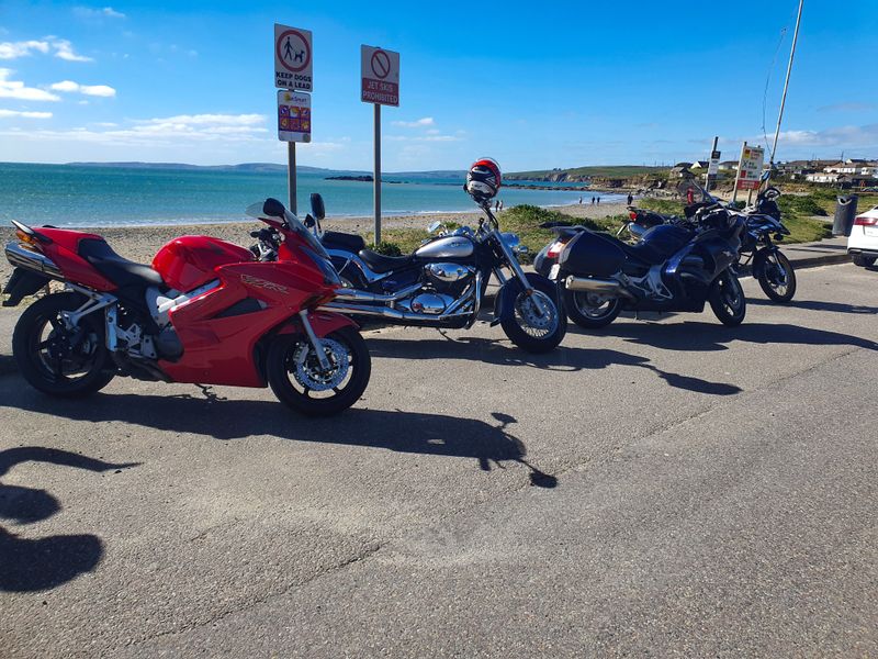 Four motorcycles parked beside beach signs on the Irish coast