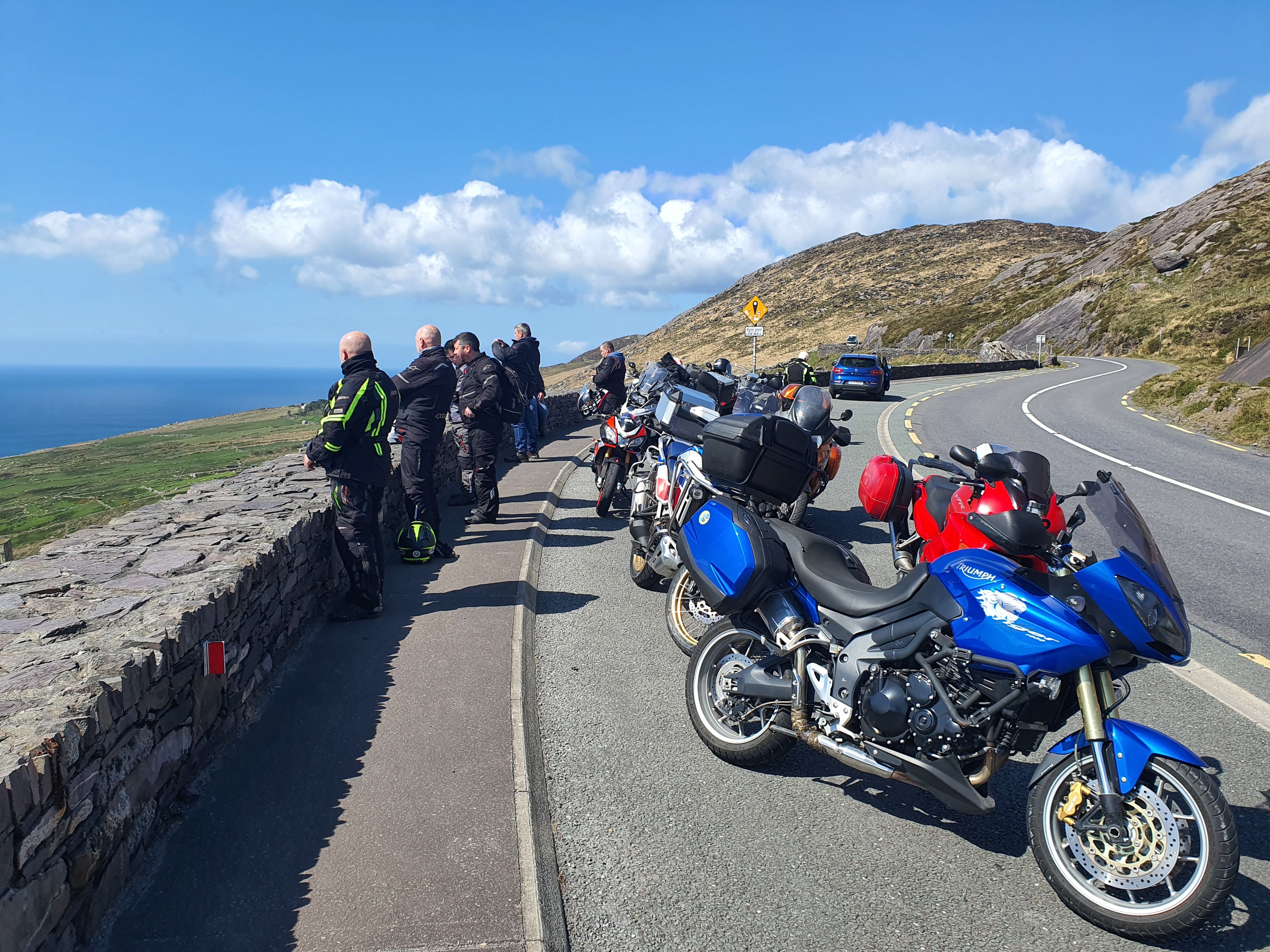Riders and their bikes pulled in on a stone-walled coastal pass