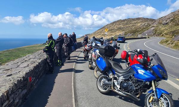 Riders and their bikes pulled in on a stone-walled coastal pass