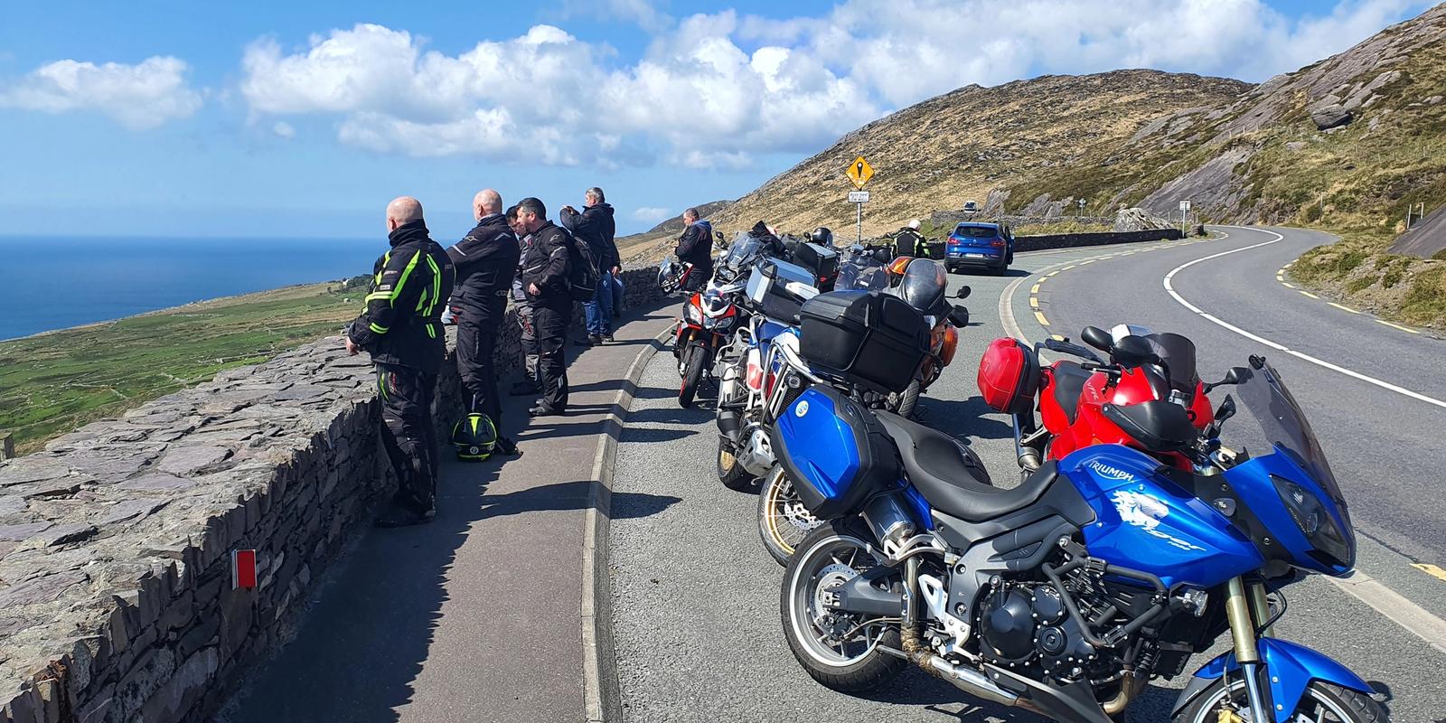Riders and their bikes pulled in on a stone-walled coastal pass