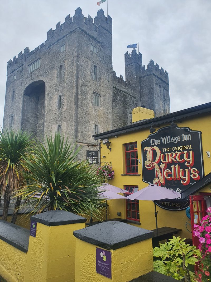 Durty Nelly's yellow pub and the stone tower of Bunratty Castle in County Clare