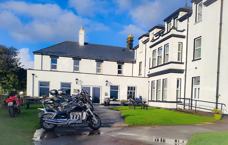 Touring motorcycles parked outside a white period country-house hotel on a sunny Irish morning