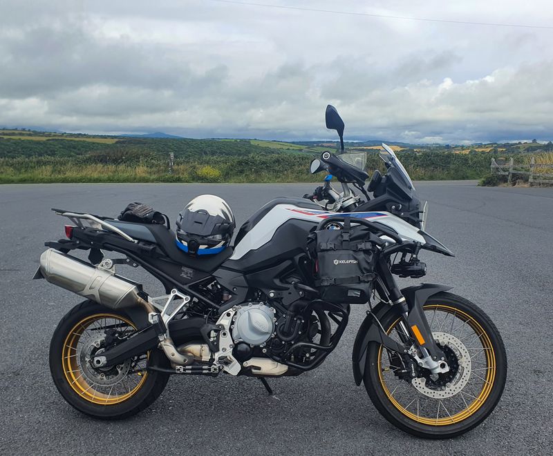 BMW F850GS adventure motorcycle with helmet on the seat, parked on a quiet country road