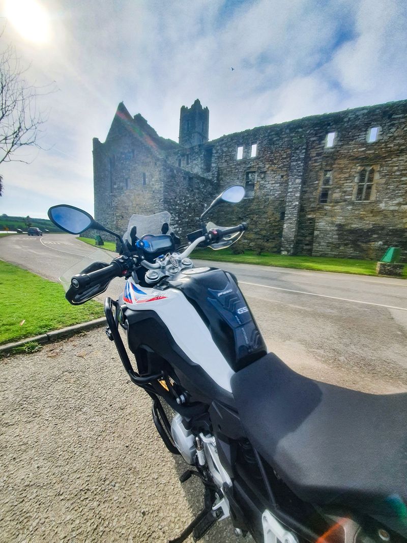 BMW F850GS parked on the road beside a ruined medieval Irish abbey