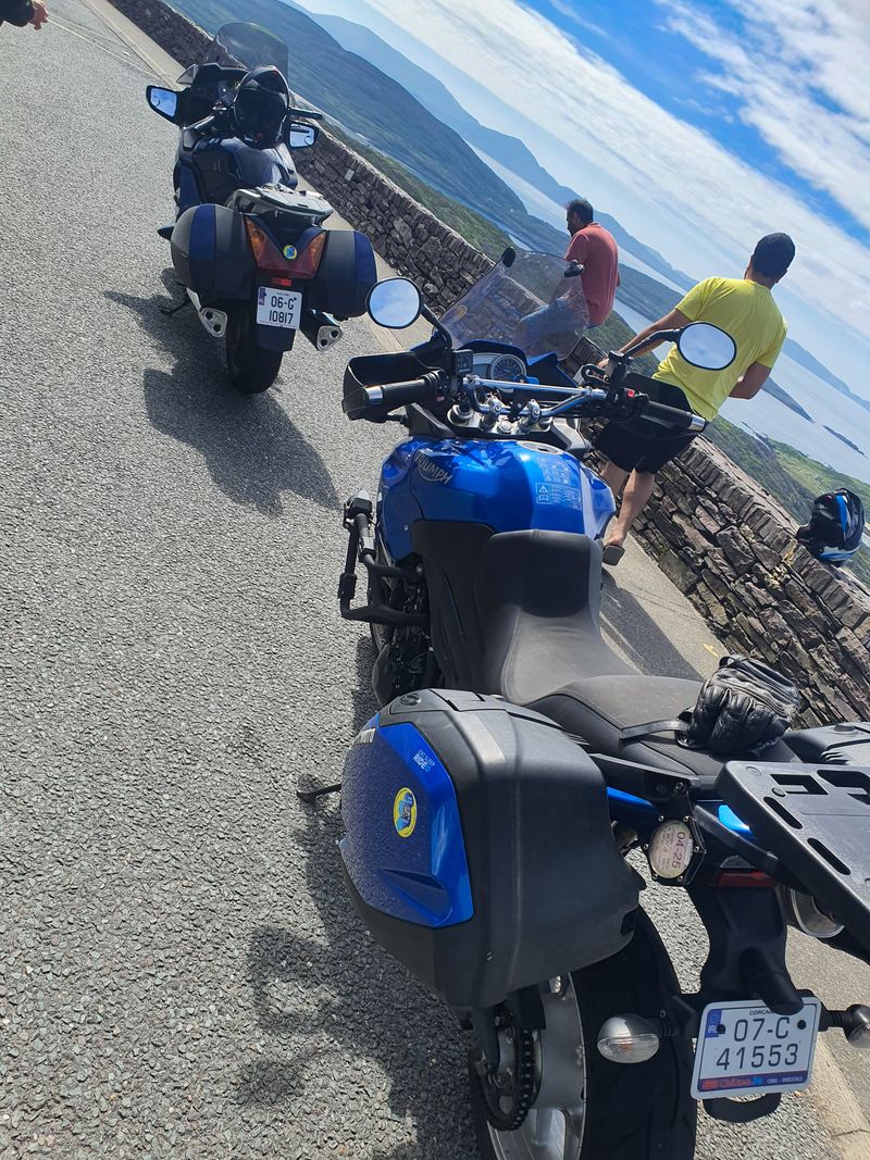 Motorcycles parked beside a stone wall at a coastal viewpoint on the Ring of Kerry