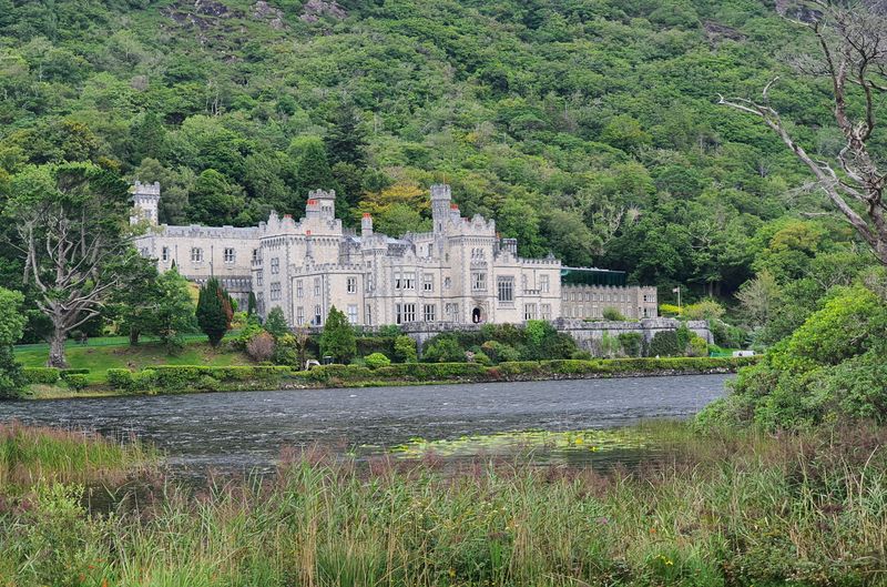 Kylemore Abbey framed by dense green woodland across its lake in Connemara