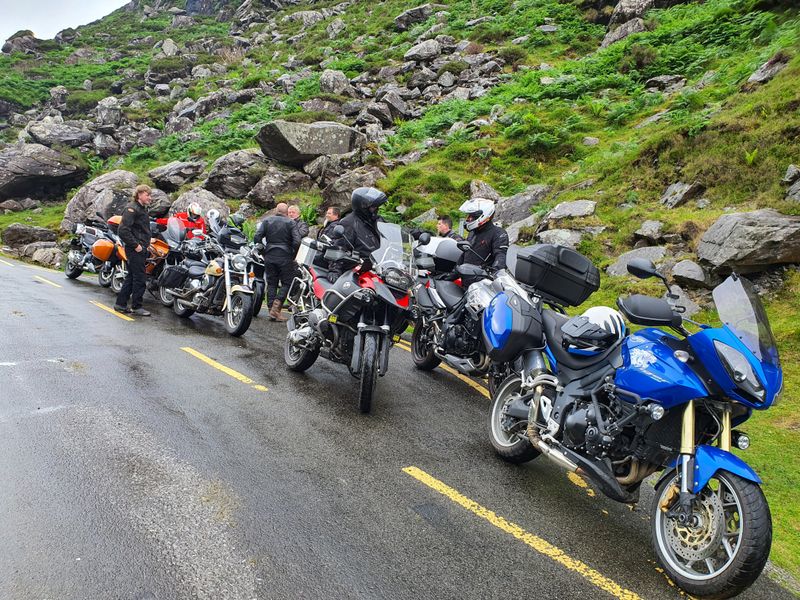 A line of touring motorcycles parked along the rocky mountain road in the Gap of Dunloe on a group tour