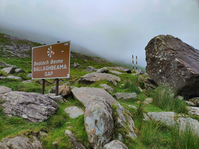 Ballaghbeama Gap road sign among rocks with mist over the Kerry mountains