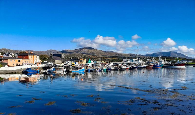 Fishing boats moored in Castletownbere harbour on the Beara Peninsula with mountains rising behind the town