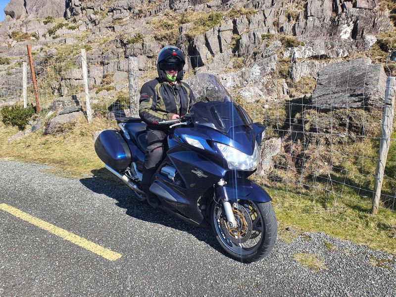 Motorcyclist paused on a Honda ST1300 beside a rocky mountain pass road in south-west Ireland