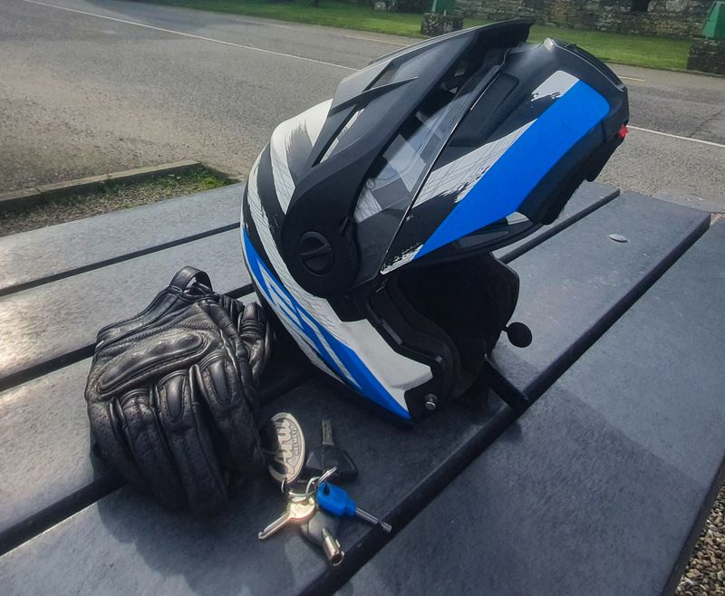 Motorcycle helmet, leather gloves and keys resting on a picnic table before a ride