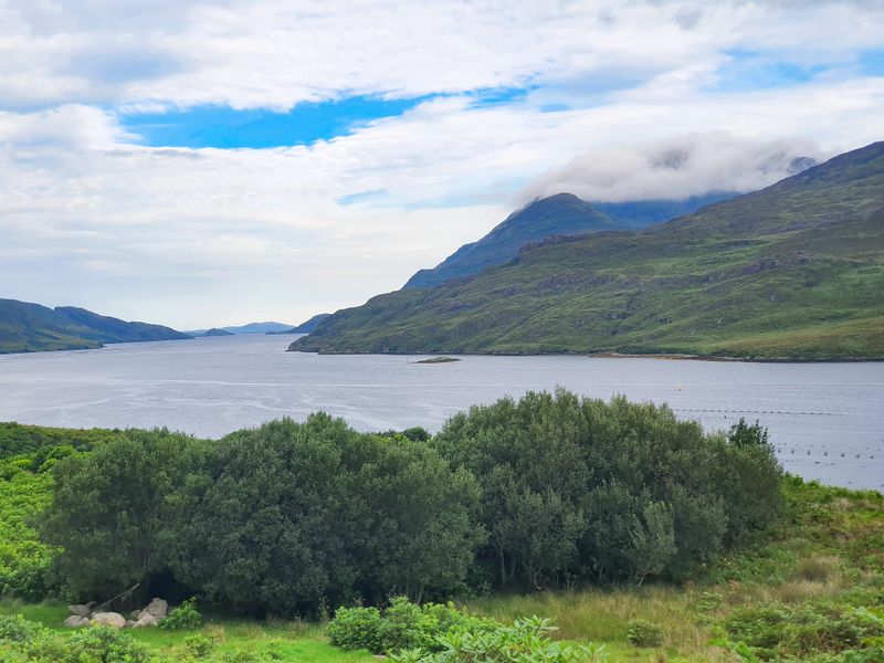 Killary Fjord in Connemara with green hills sloping into calm grey water under a cloudy sky
