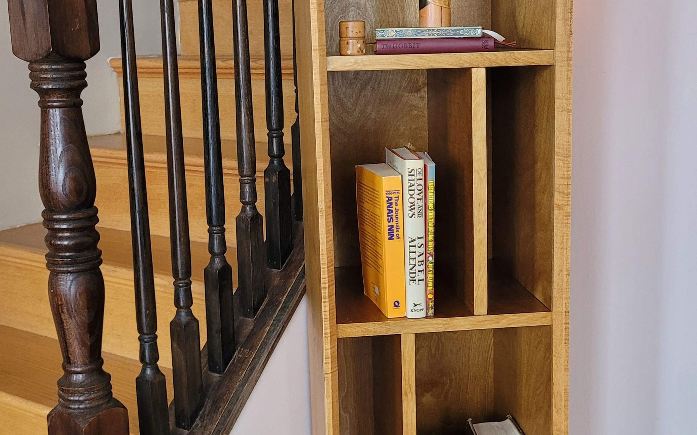 Tall narrow bookcase on tapered legs, filled with books and a lantern on top