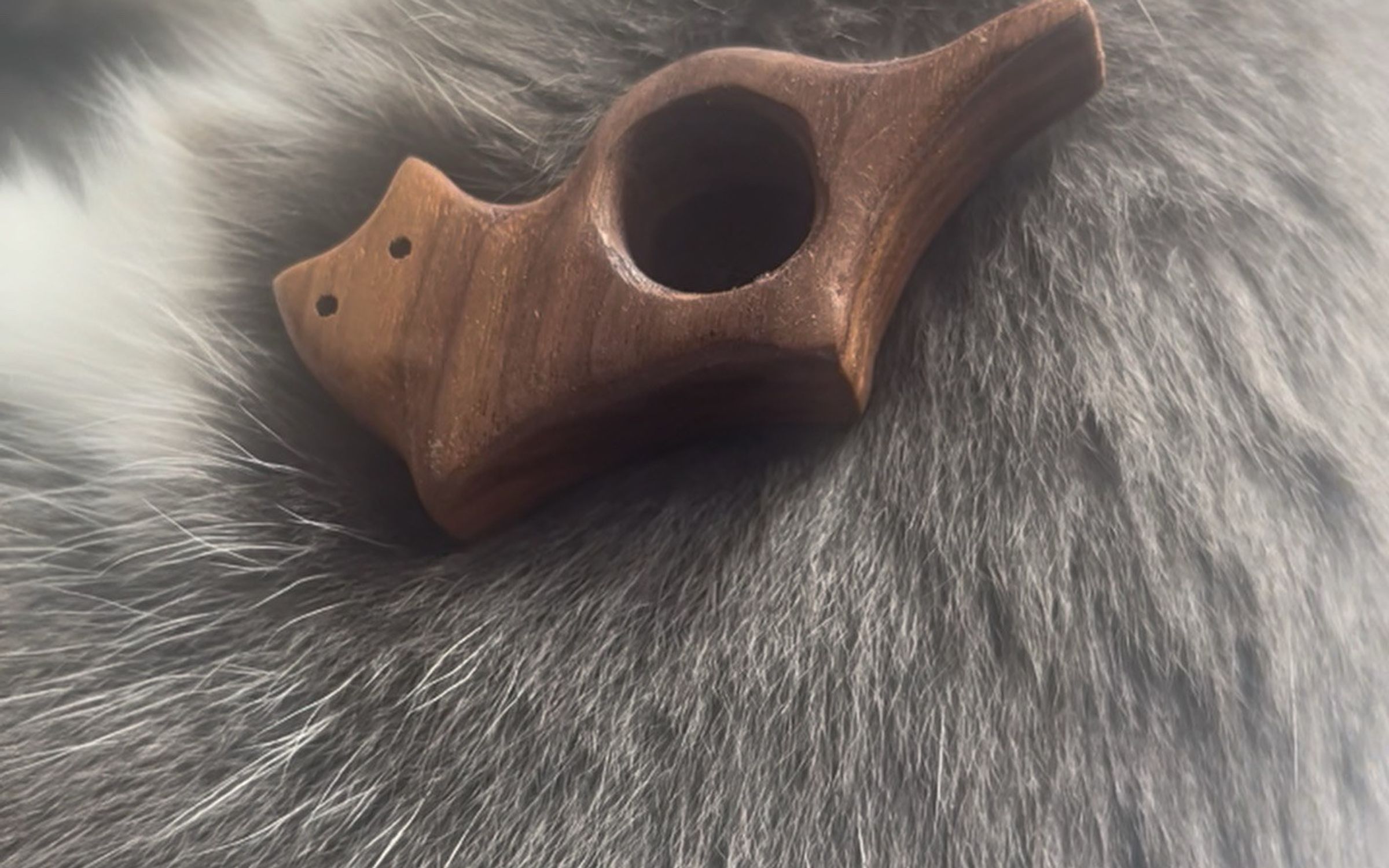 Small hand-carved wooden cat resting on a grey cat