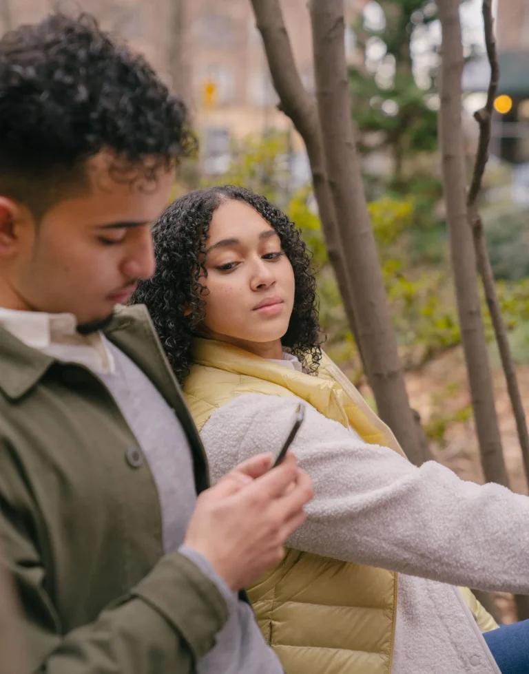 A woman glancing at a friend’s phone, seeing what once took asking