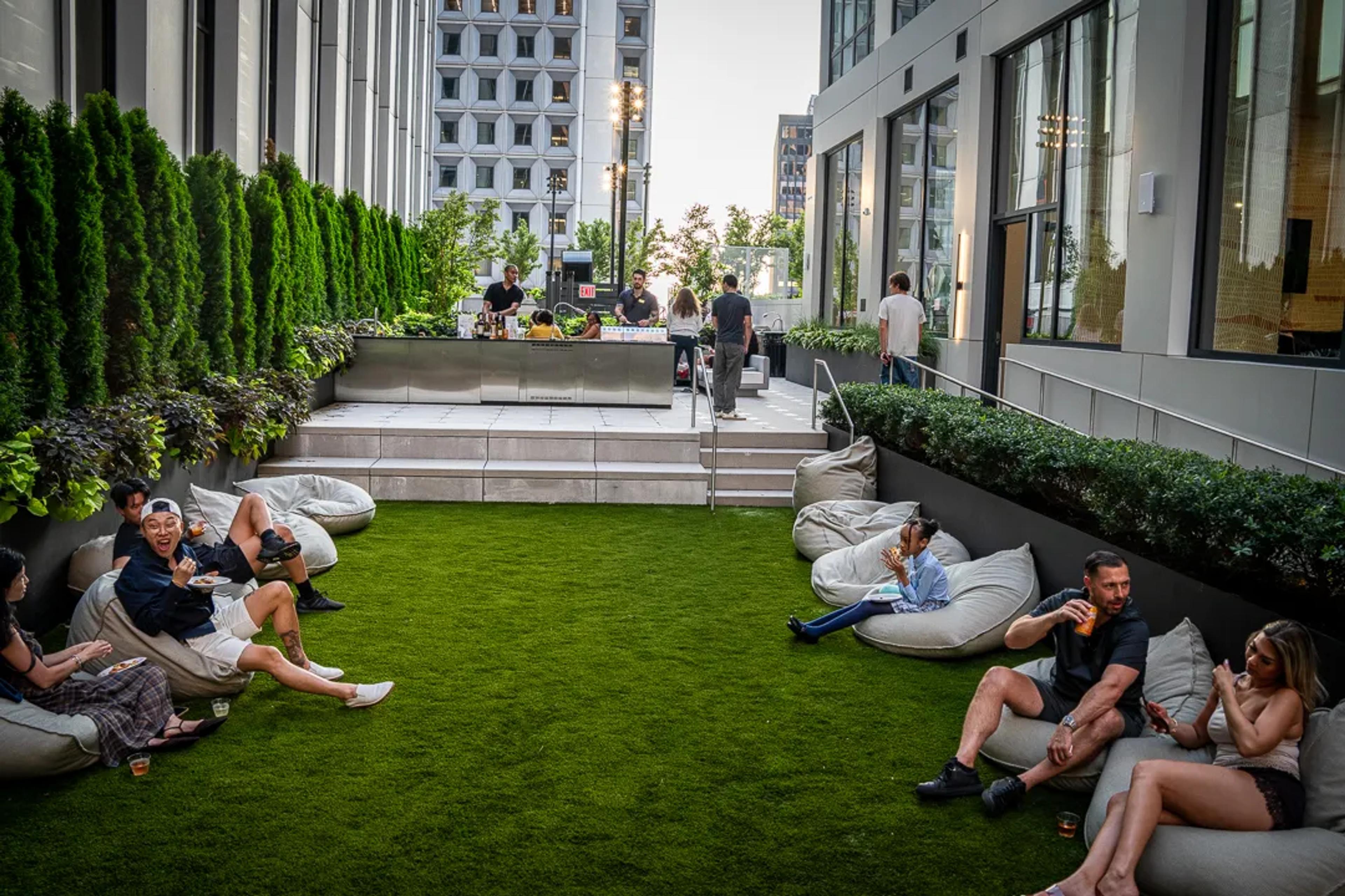 Guests lounging on beanbags on the rooftop lawn, the office towers at the far end