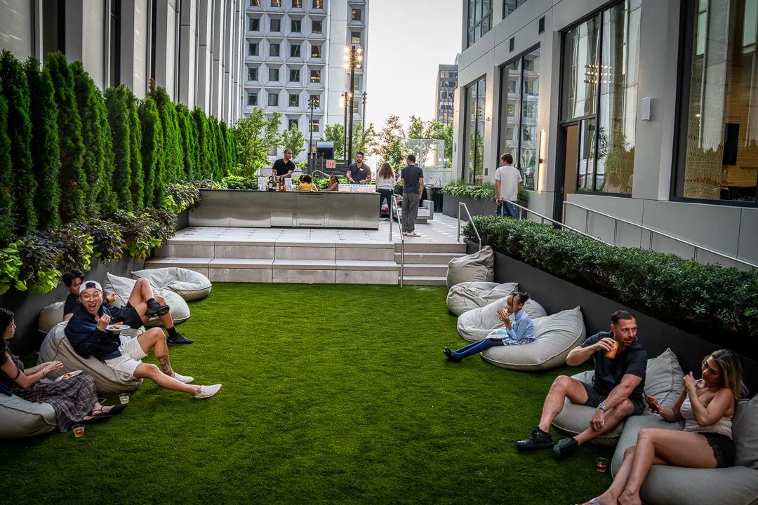 Guests lounging on beanbags on the rooftop lawn, the office towers at the far end