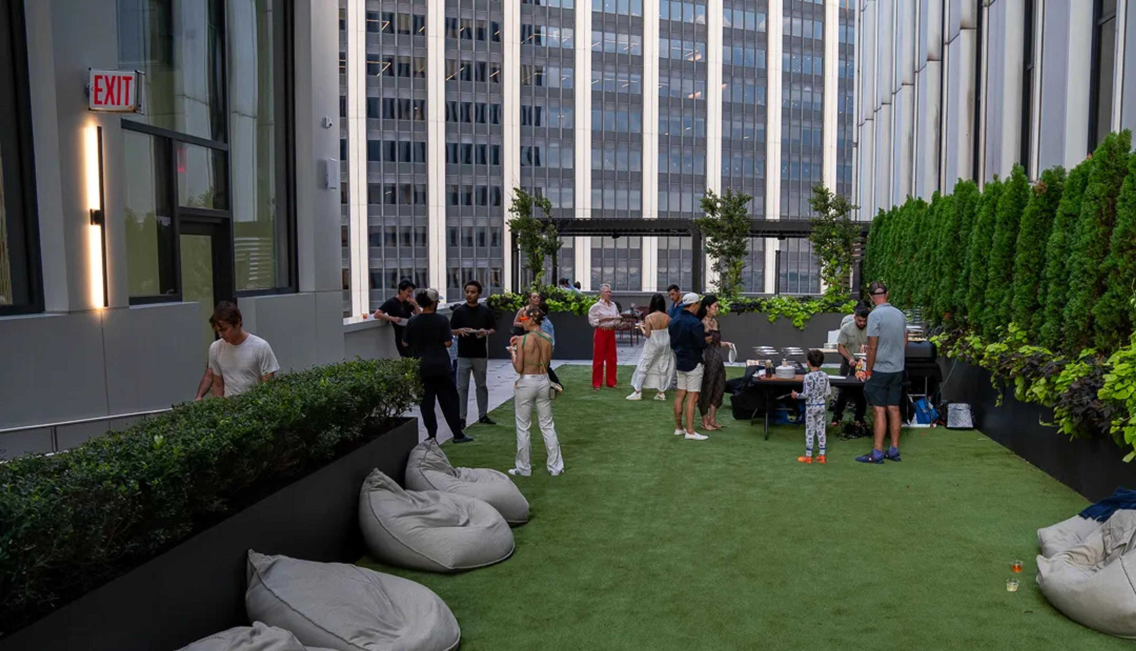 The length of the rooftop lawn, beanbags along the hedge and the service table at the far end under the towers