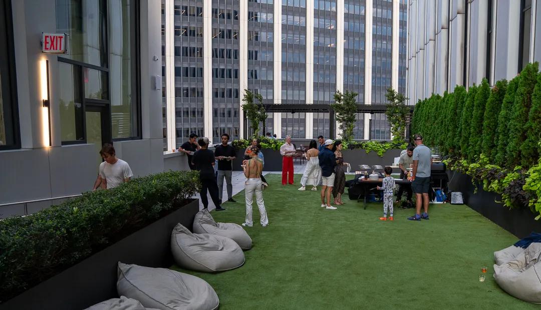 The length of the rooftop lawn, beanbags along the hedge and the service table at the far end under the towers