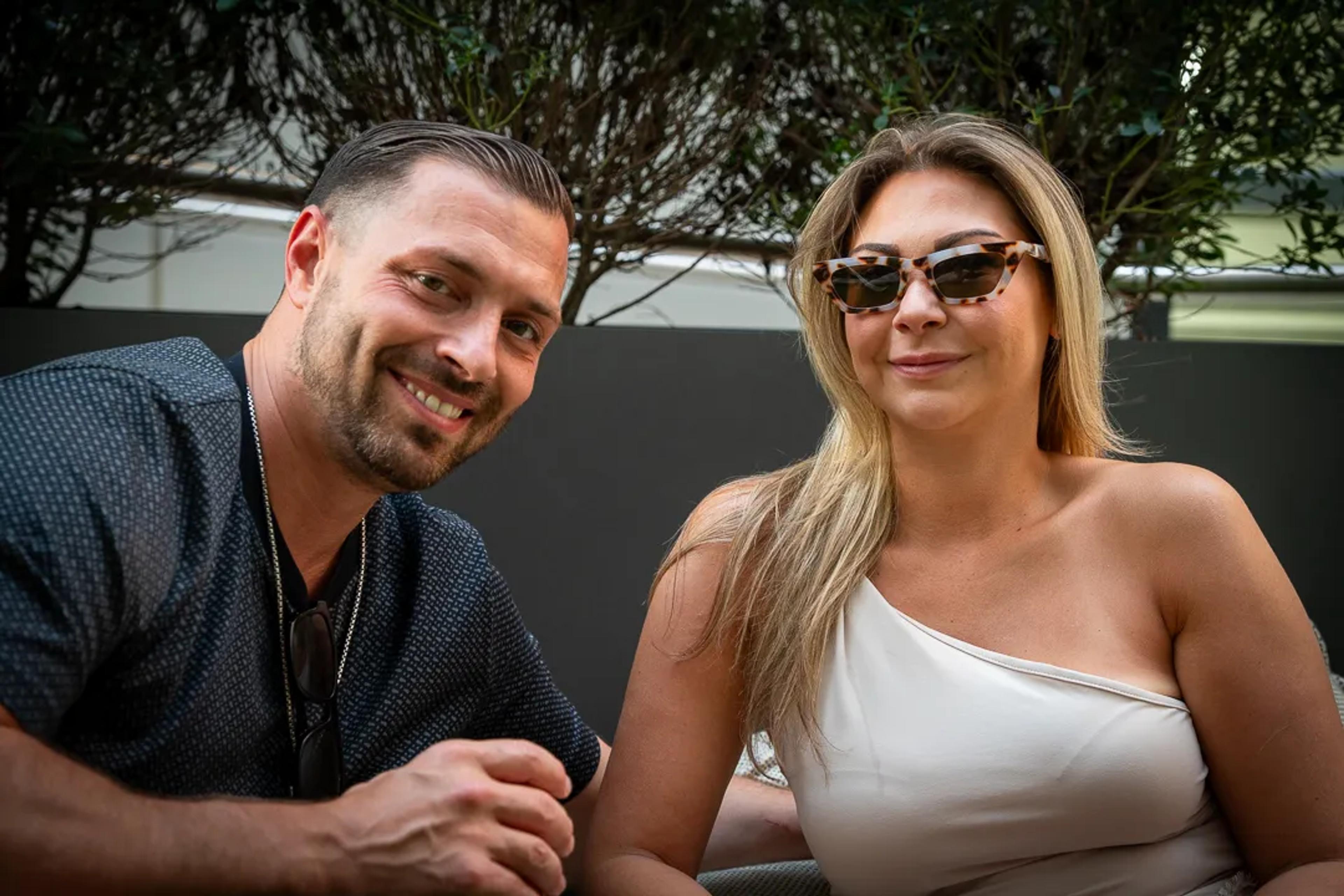 Two guests smiling at a table on the roof deck