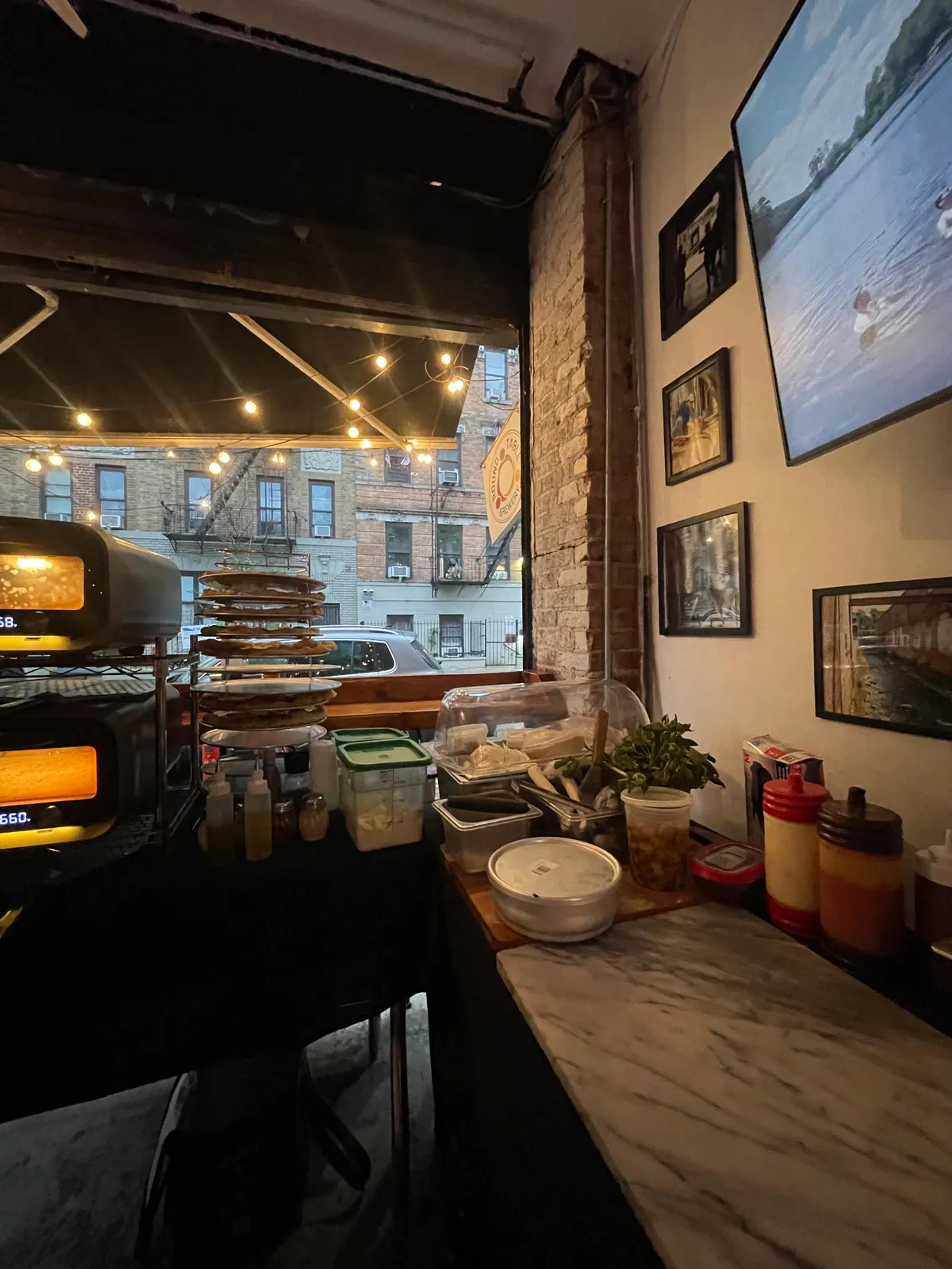 Two ovens heating at the taproom's front window, the prep laid along a marble counter under framed photographs