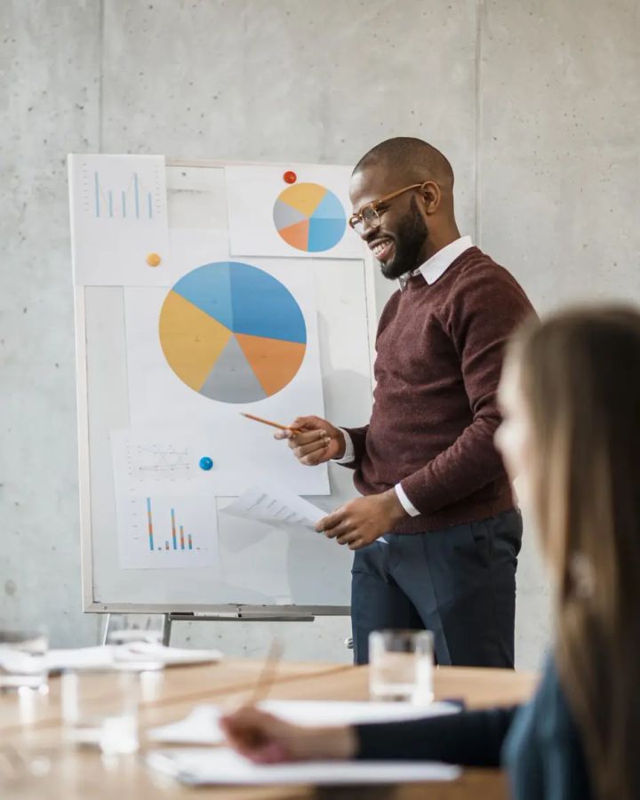 Un consultant commente un graphique circulaire devant une équipe réunie.