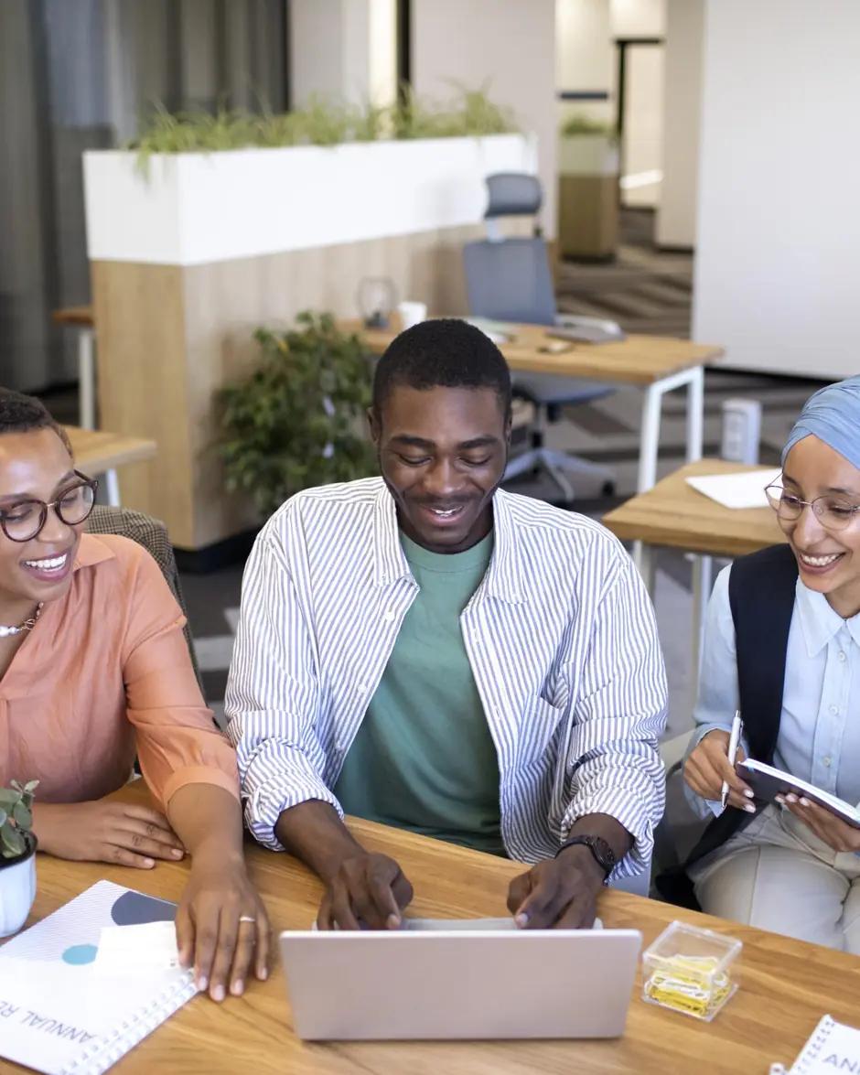 Trois jeunes professionnels travaillent ensemble autour d'un ordinateur portable.