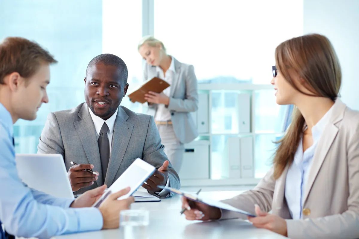 Un dirigeant échange avec ses collaborateurs autour d'une table de réunion.