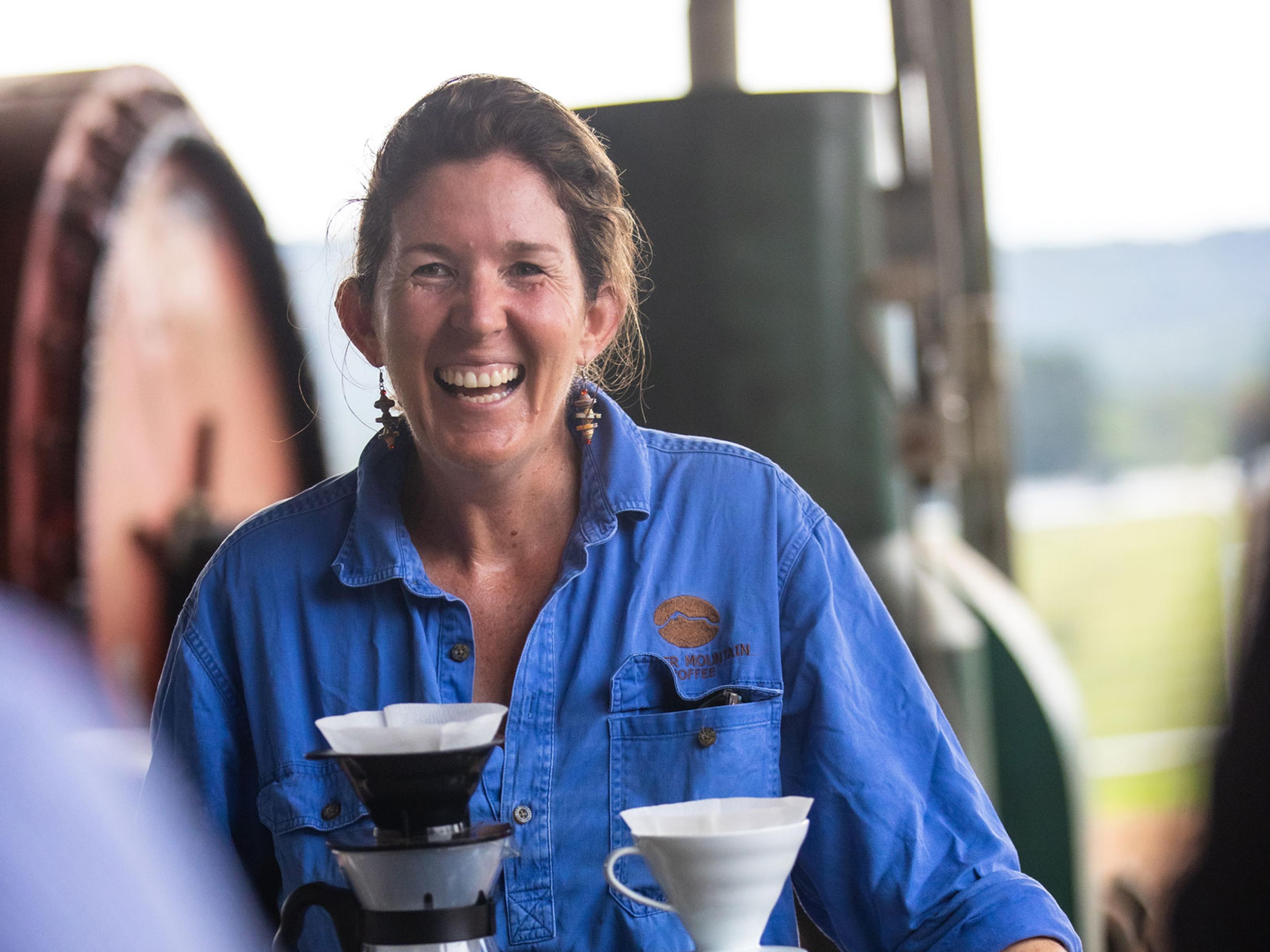 A smiling woman is holding a coffee filter