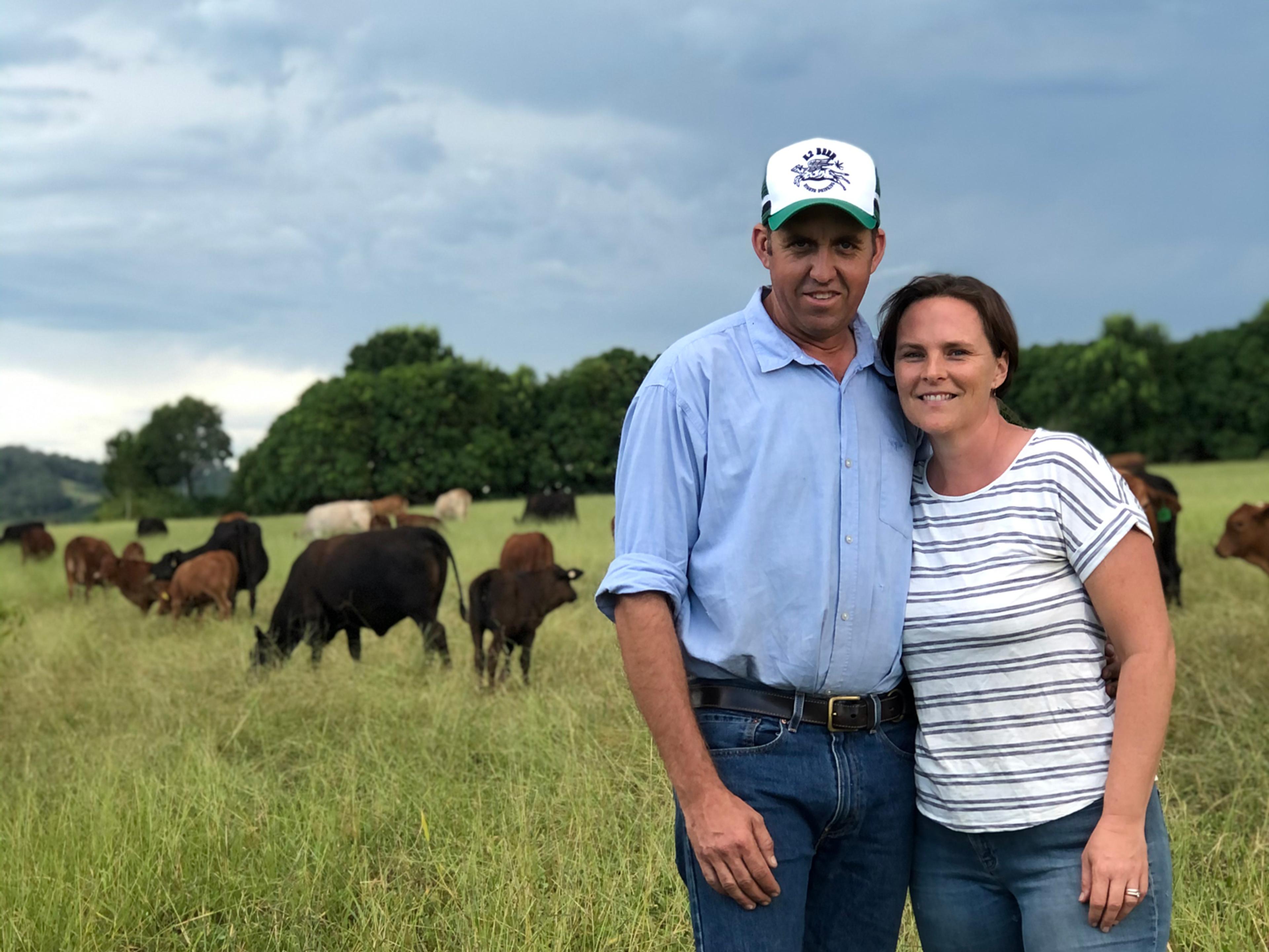 Kandanga Farm Store founders Tim & Amber Scott on their Mary Valley property. They are standing in a paddock with cows in the background.