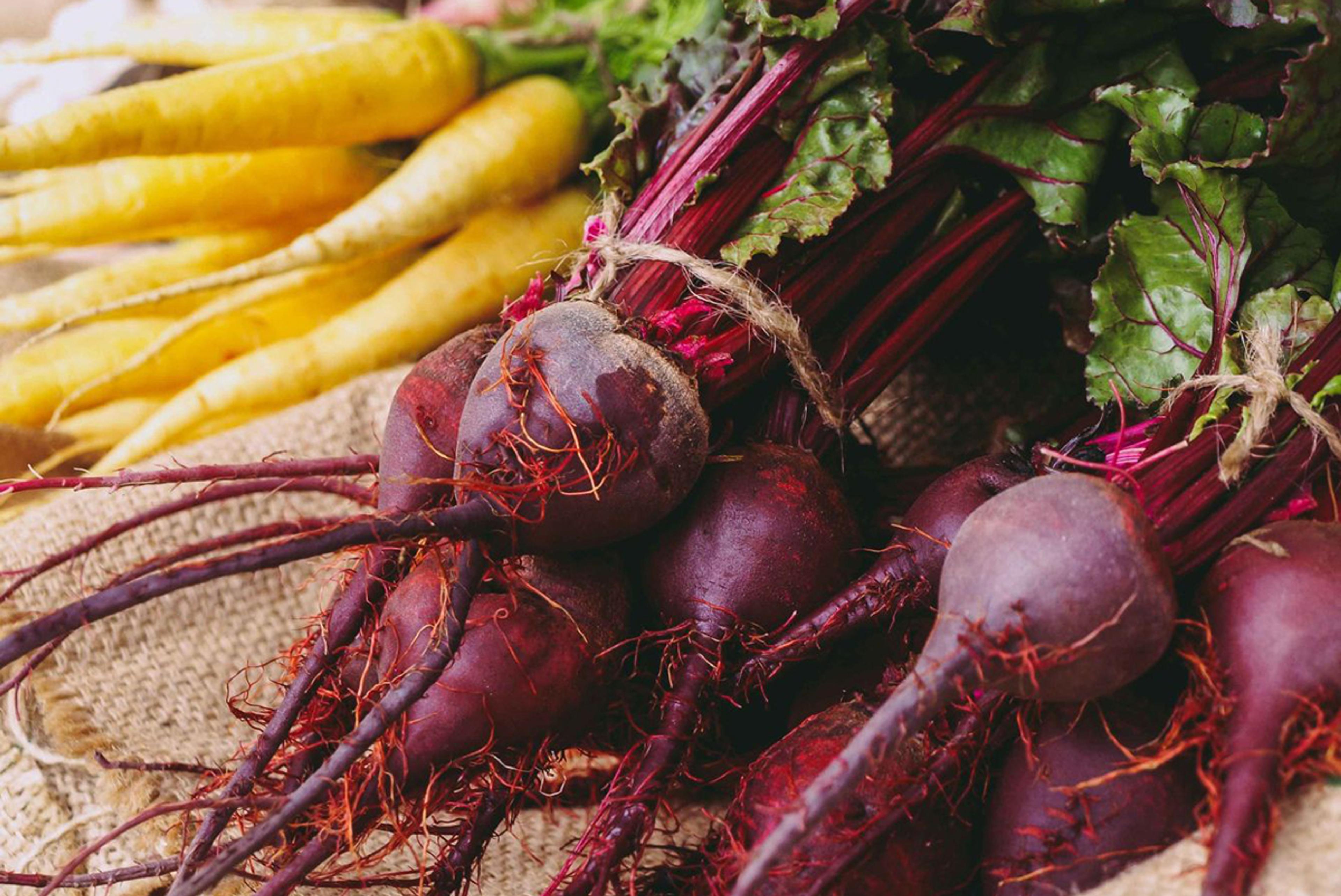 Carrots and beetroots on hessian material.