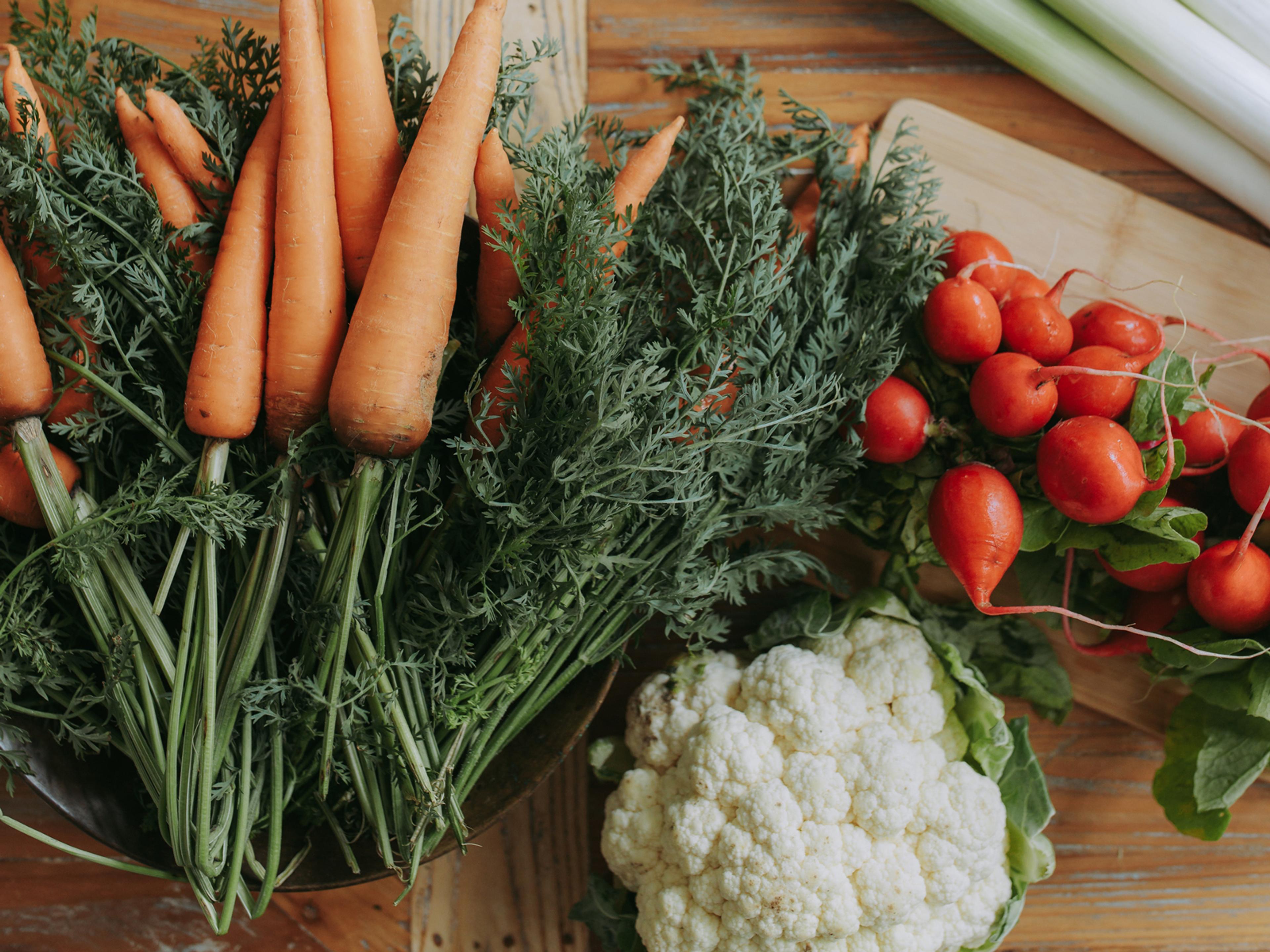 Carrots, radishes and cauliflower on a board.