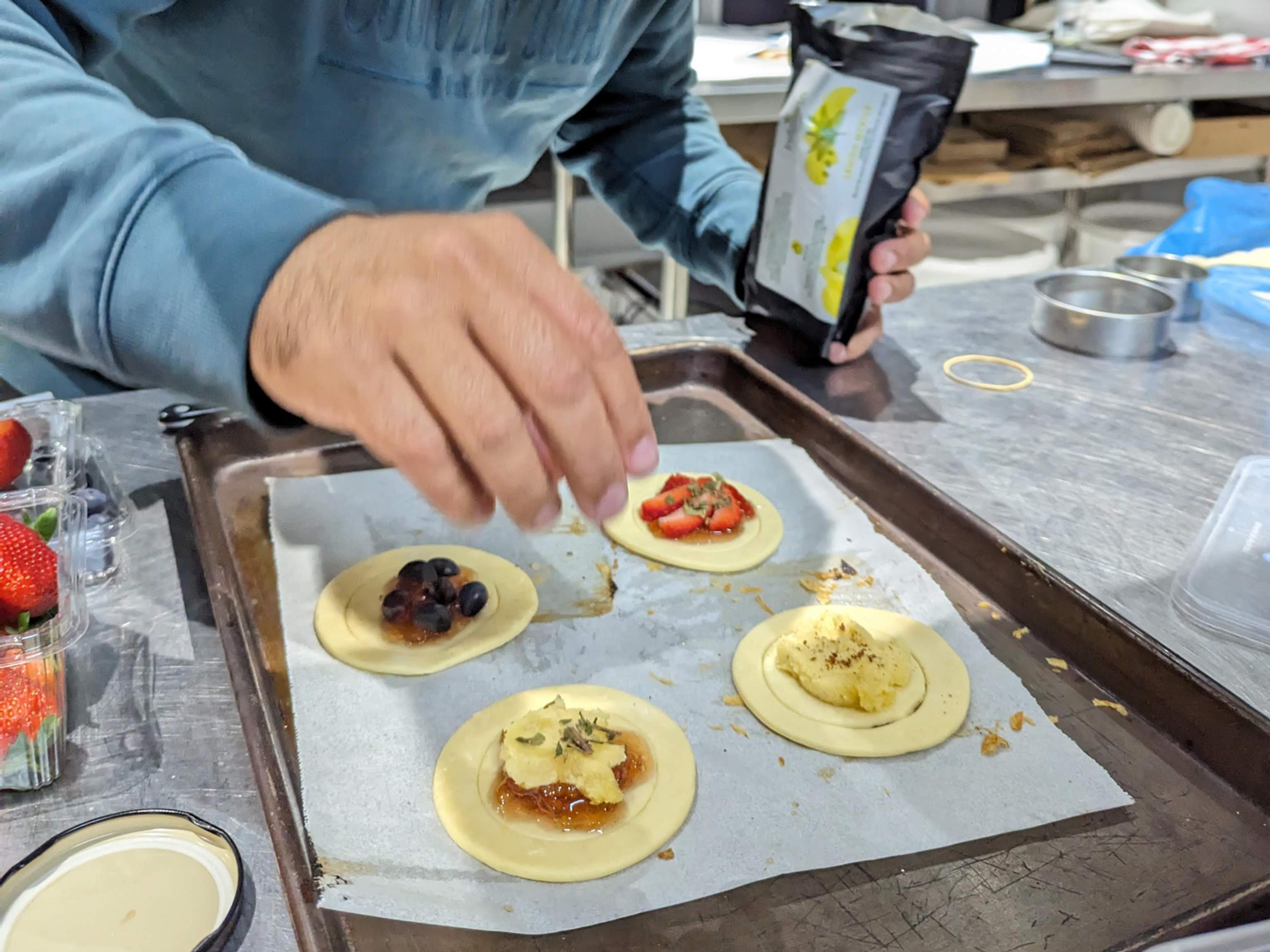 Gamilaraay Man and Director of Native Foods at Native Foodways - Corey Grech - adding Lemon Myrtle to some native pastries in the Native Foodways test kitchen.