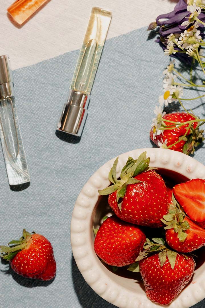 A picture of sniph 8 ml perfumes on a white an blue fabric with strawberries and flowers