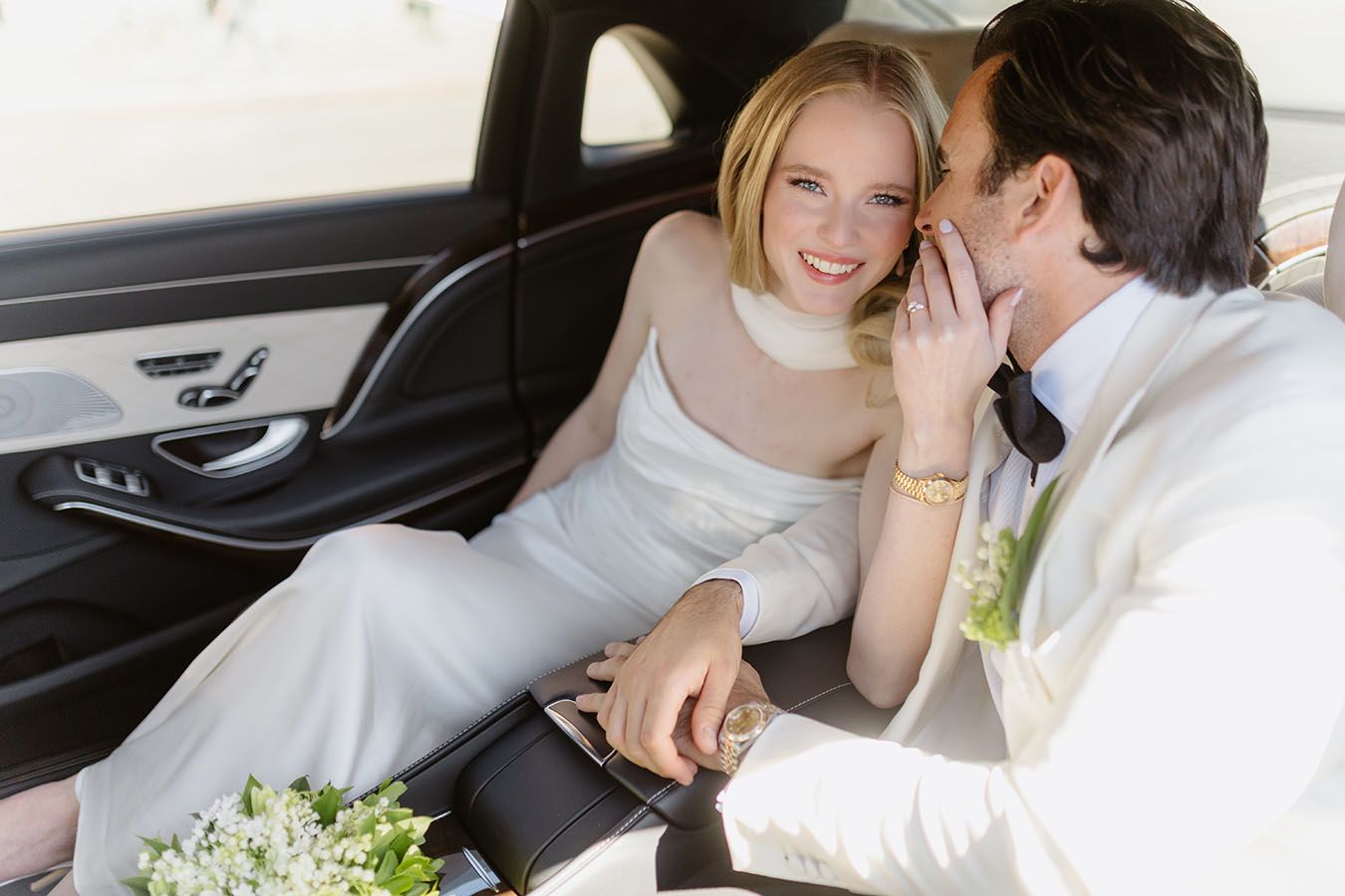 A couple dressed in wedding dress seated in a car.