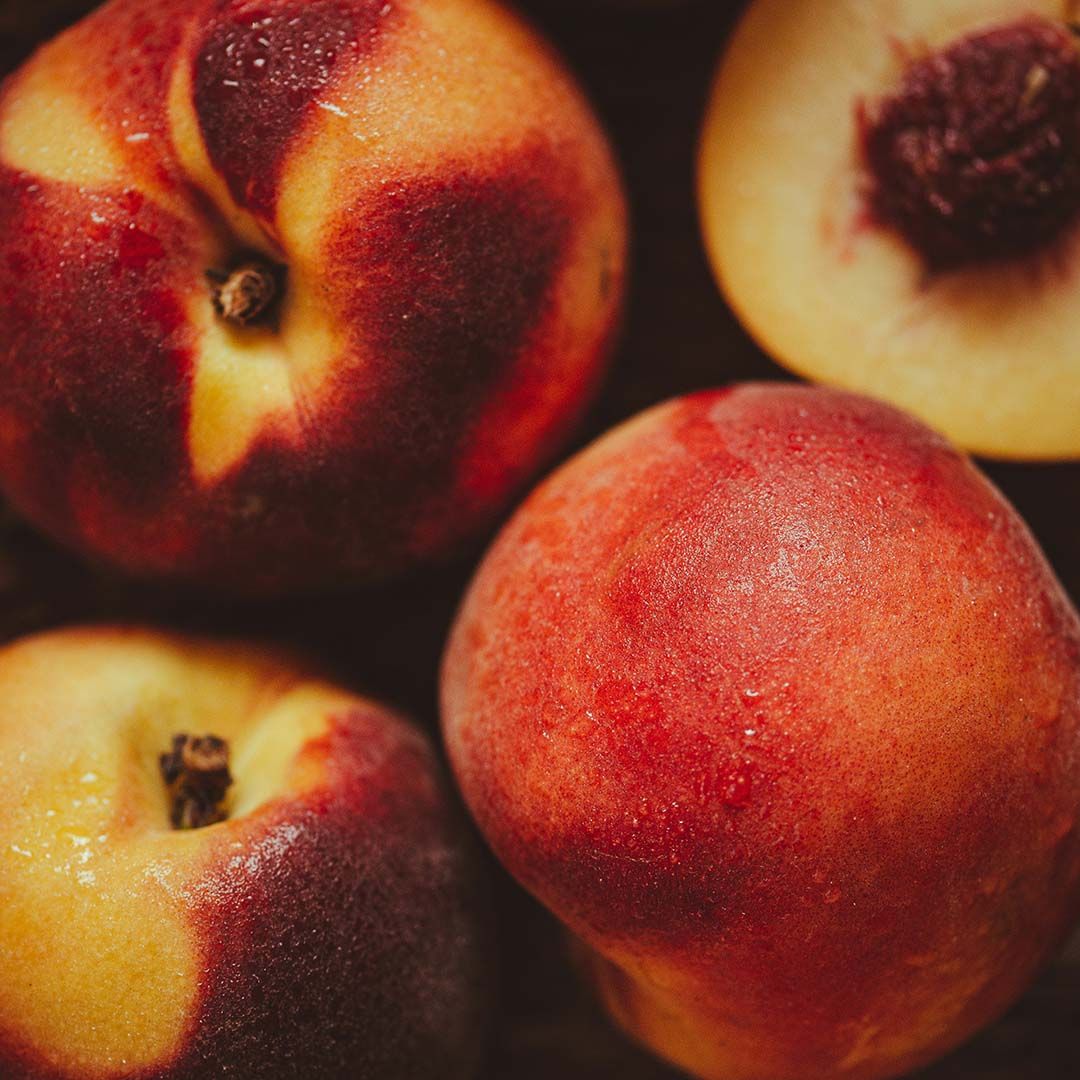 A closeup on whole and half peaches.