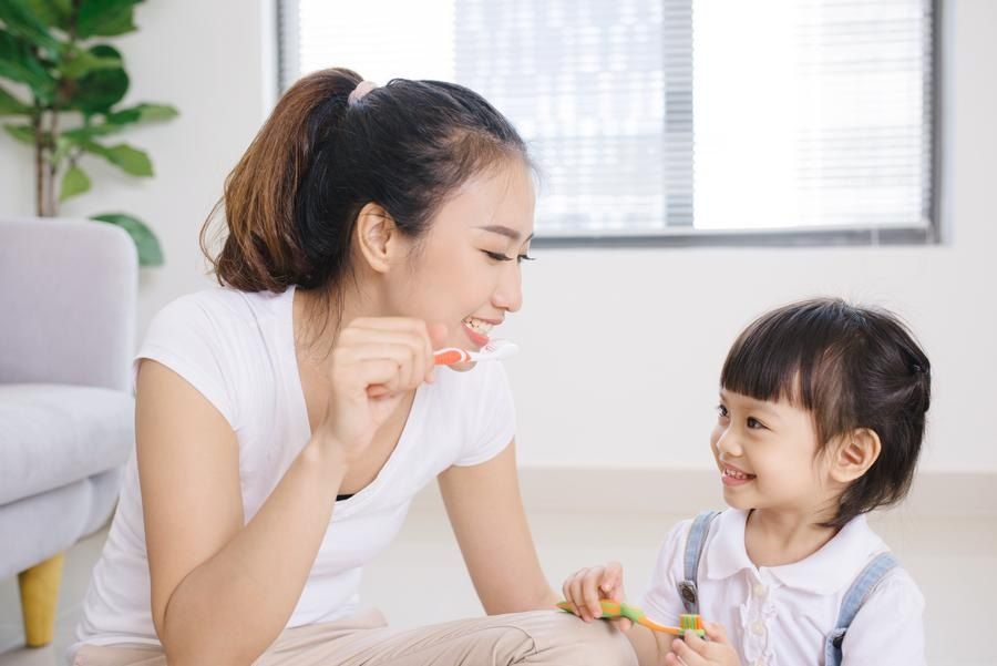 Asian mom in Berkeley CA teaches daughter how to brush teeth