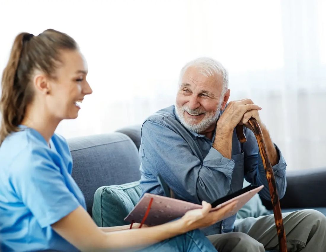 A TAMCARE caregiver chatting with a senior client at home