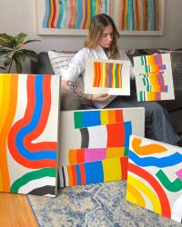 Amber Vittoria Holding Her Paintings while sitting on a couch