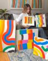 Amber Vittoria Holding Her Paintings while sitting on a couch