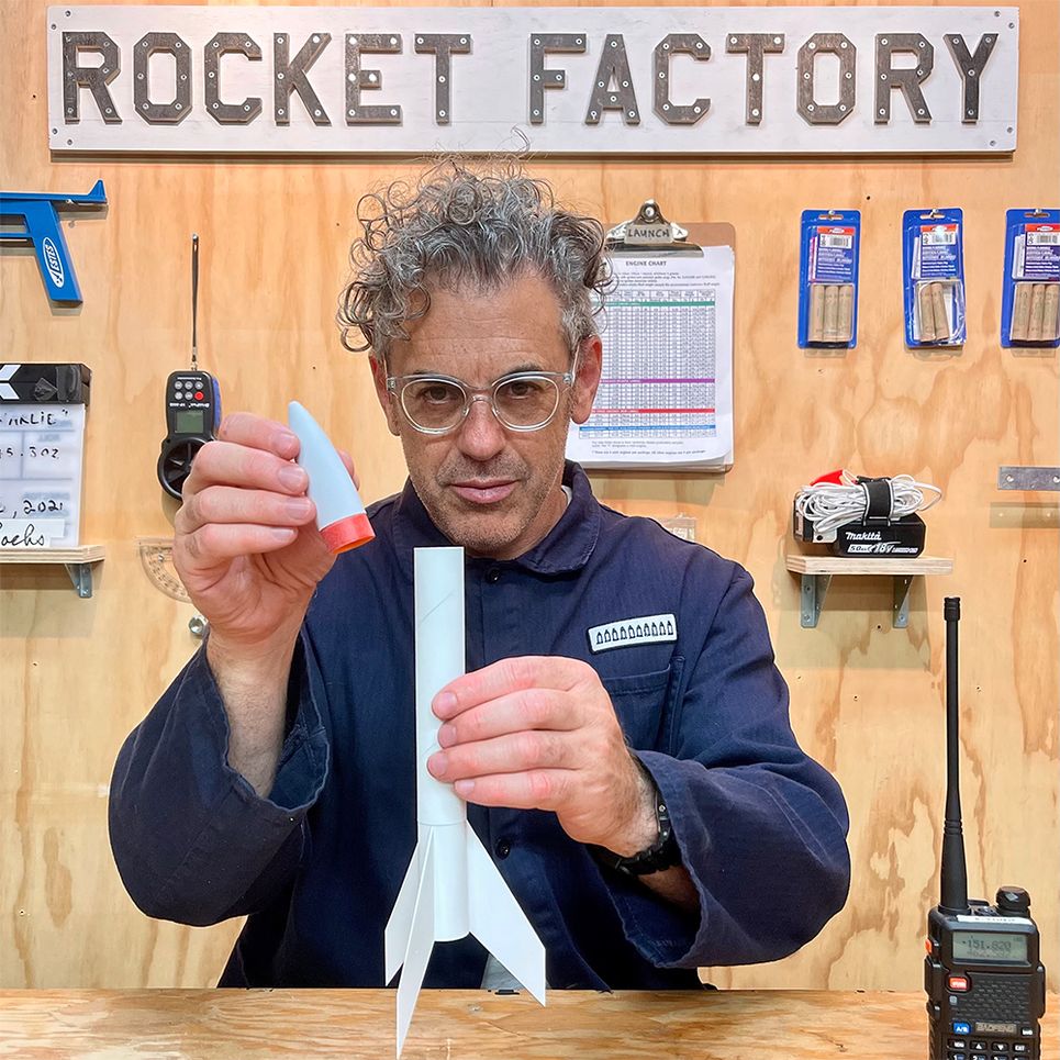 Tom Sachs assembling a plain white rocket