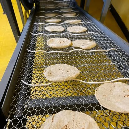 Tortillas de maíz recién hechas enfriándose en la banda de la tortillería