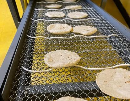 Tortillas de maíz recién hechas enfriándose en la banda de la tortillería