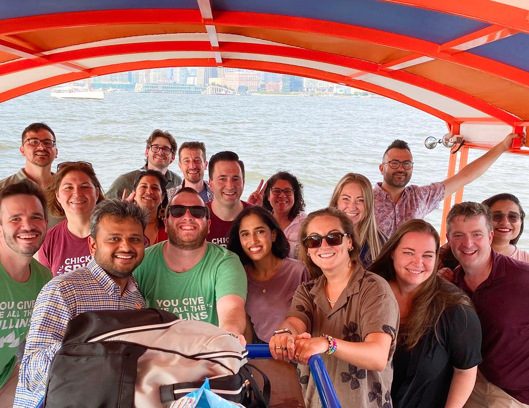 Team photo, medium group of people smiling on a boat with ocean view behind them