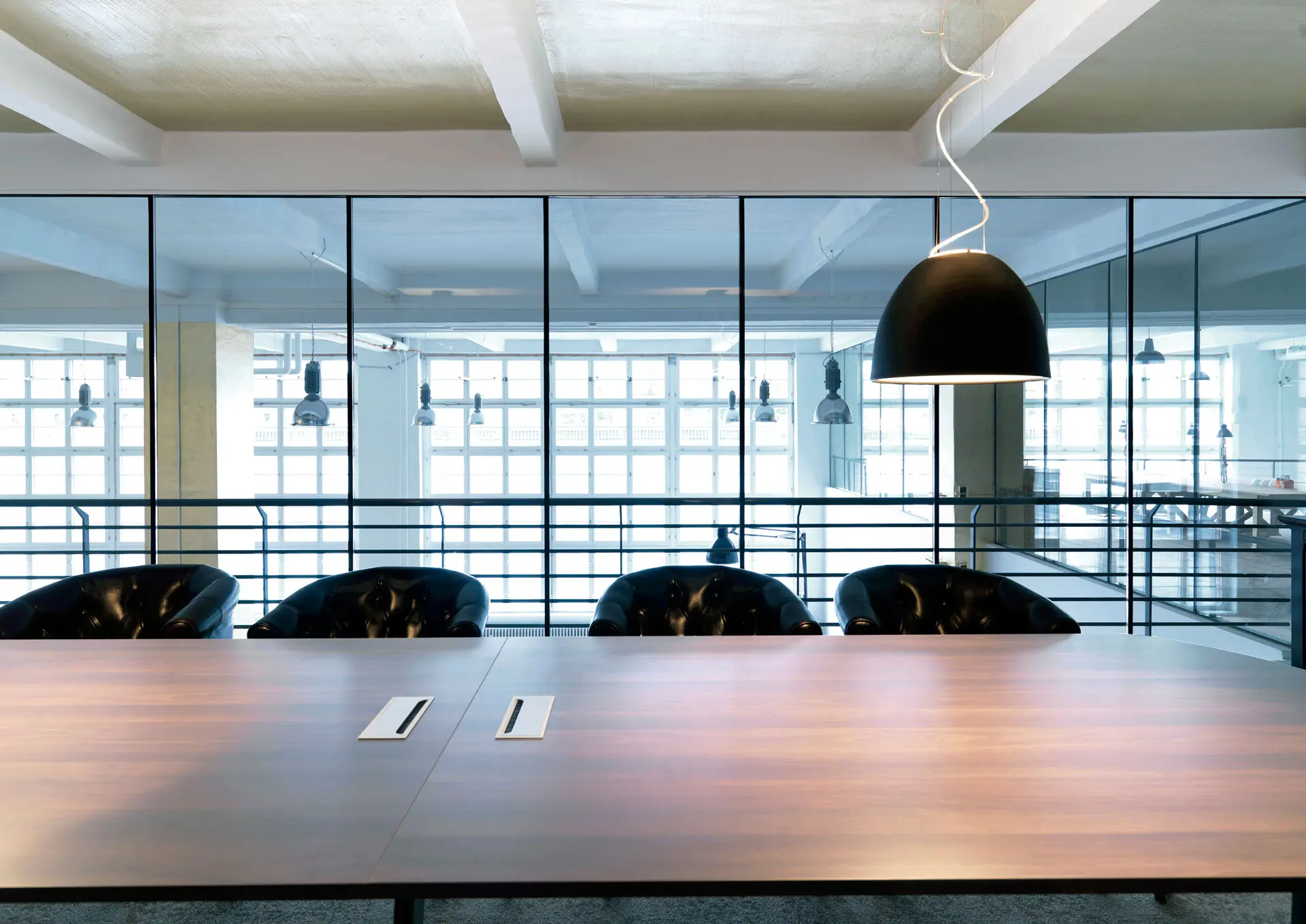 A photo of an office with wooden furniture and big windows in industrial style