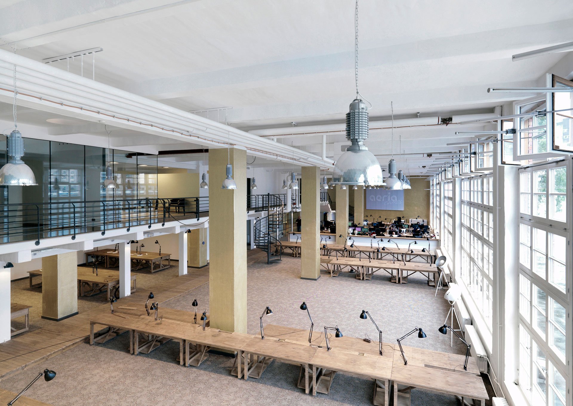 A photo of an office with wooden furniture and big windows in industrial style