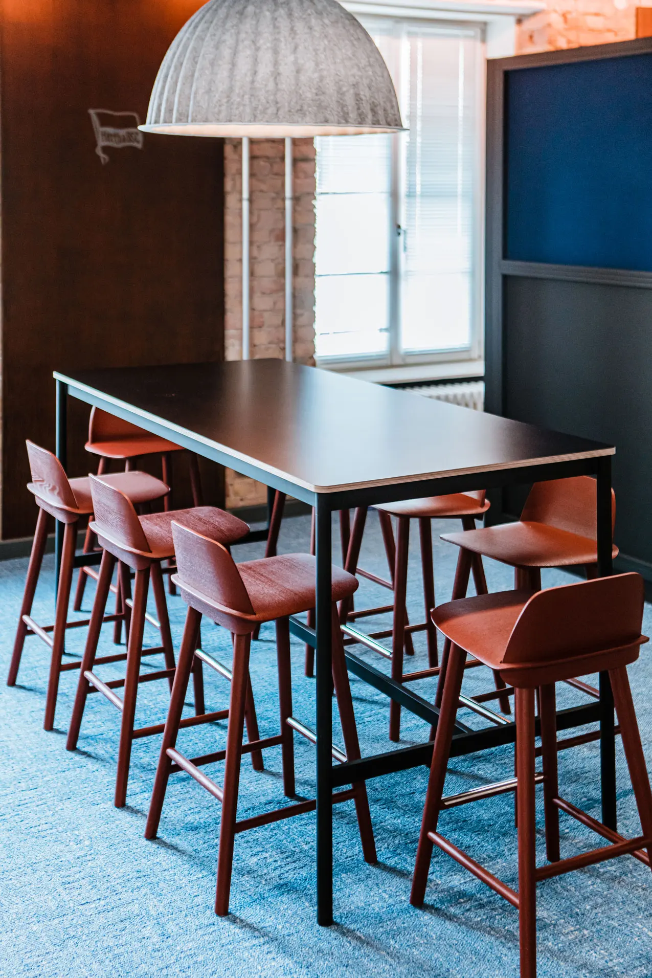 Meetingbereich mit schwarzem Konferenztisch und roten Stühlen