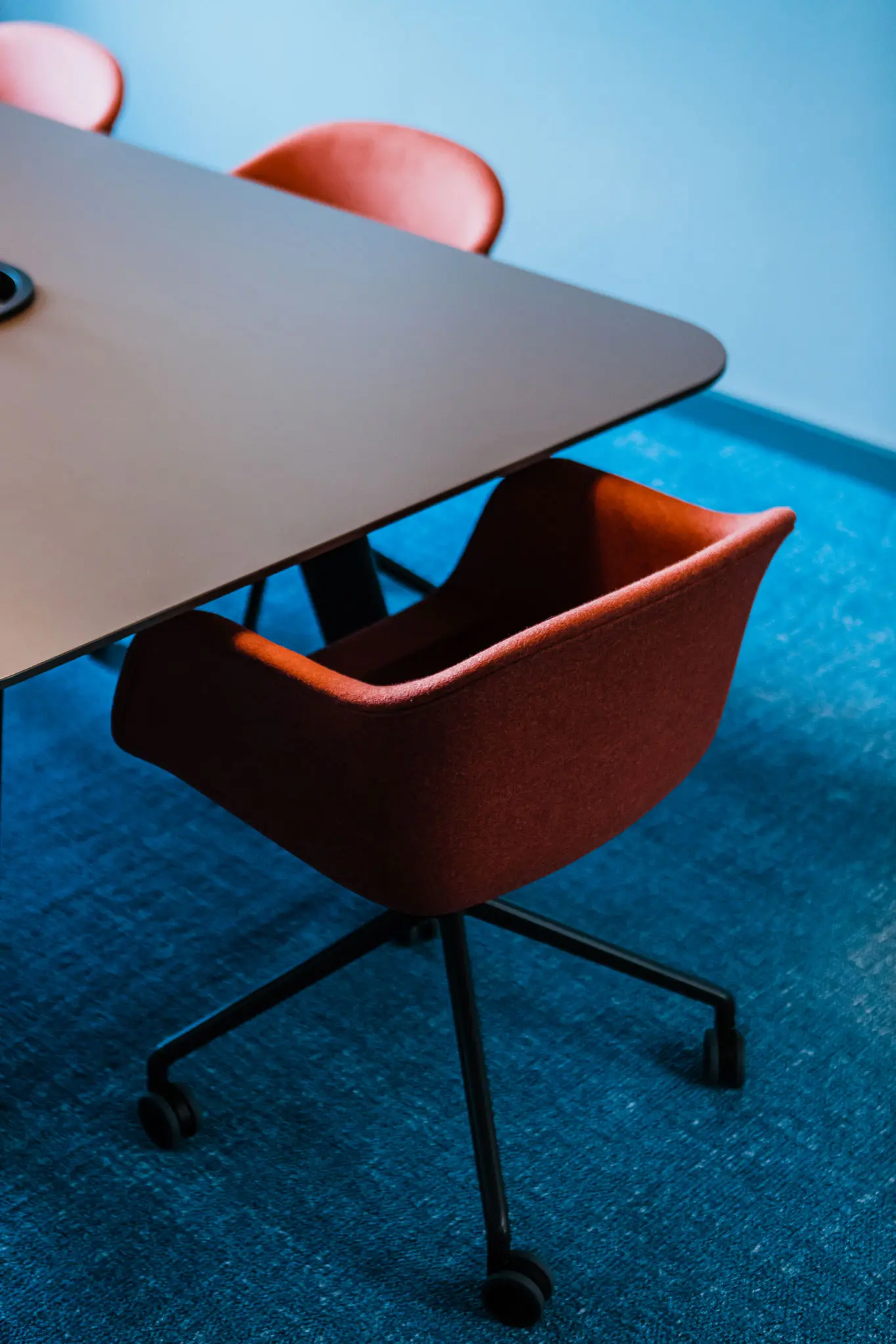 Nahaufnahme schwarzer Tisch und roter Bürodrehstuhl 